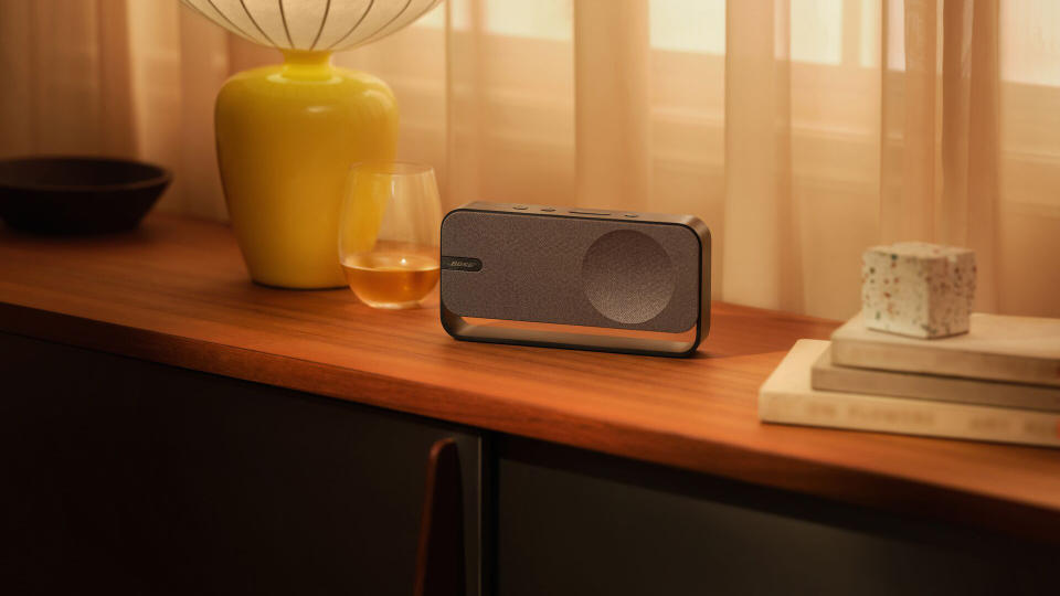 Το ηχείο Bose SoundLink Home κάθεται σε ένα ράφι δίπλα σε ένα ποτήρι. Εικόνα μάρκετινγκ τρόπου ζωής.