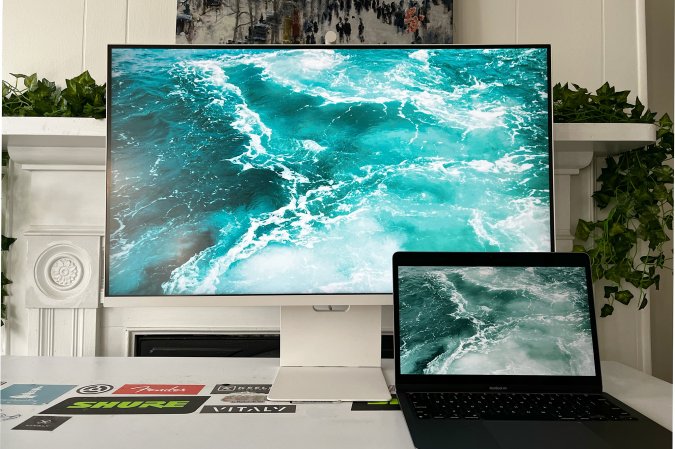  A white Samsung M8 sitting next to a space gray MacBook Air